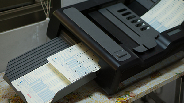Filled-out scantrons being processed in a scantron reader